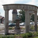 Gesamtansicht des Duncker-Denkmals vor dem Bahnhof Rathenow mit dem Wasserturm im Hintergrund