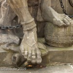 Denkmal des Großen Kurfürsten Friedrich Wilhelm Johann Georg Glume auf dem Schleusenplatz in Rathenow, Nahaufnahme von den Füßen des Sklaven an der nordöstlichen Sockelecke mit einer Granate