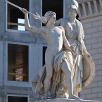 Die aus weißem Marmor aus Carrara angefertigte Skulptur "Athena unterrichtet den Jungen im Waffengebrauch" auf der Schlossbrücke in Berlin-Mitte stammt Hermann Schievelbein aus dem Jahr 1853.