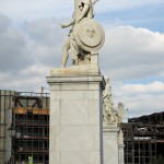 Die aus weißem Marmor aus Carrara angefertigte Skulptur "Athena unterrichtet den Jungen im Waffengebrauch" auf der Schlossbrücke in Berlin-Mitte stammt Hermann Schievelbein aus dem Jahr 1853.