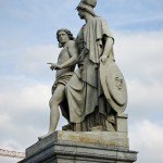 Die aus weißem Marmor aus Carrara angefertigte Skulptur "Athena unterrichtet den Jungen im Waffengebrauch" auf der Schlossbrücke in Berlin-Mitte stammt Hermann Schievelbein aus dem Jahr 1853.